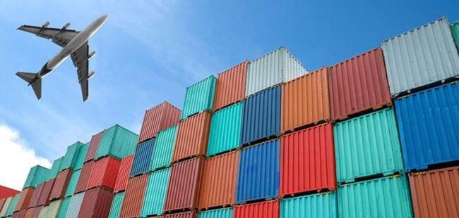 Colourful shipping containers with plane flying overhead