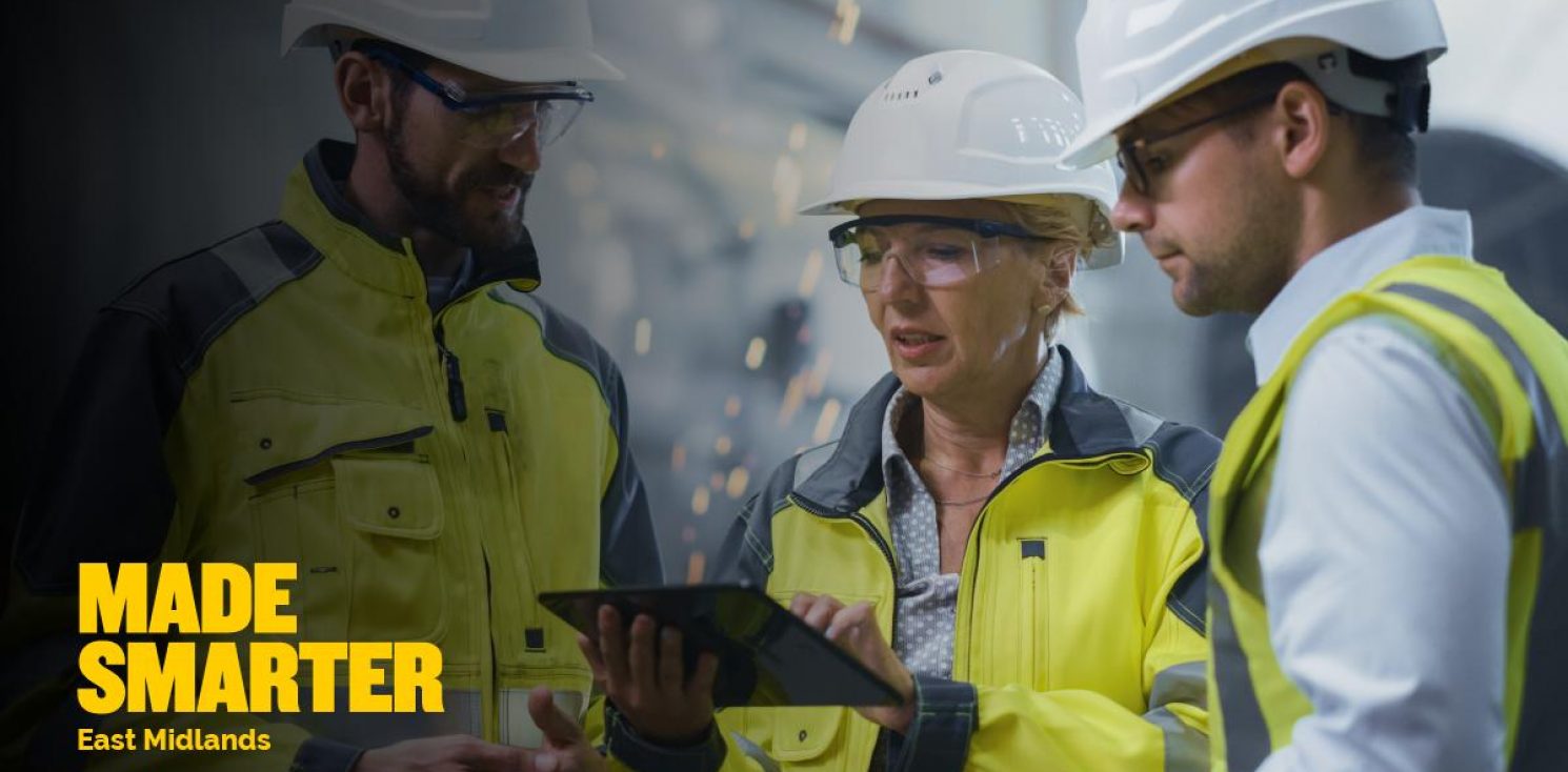 Three people in hard hats looking at electronic tablet