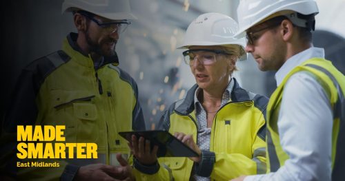 Three people in hard hats looking at electronic tablet